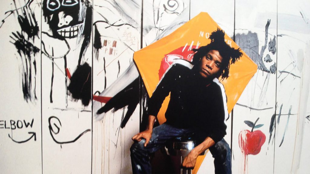Jean-Michel Basquiat ritratto davanti a una sua opera.